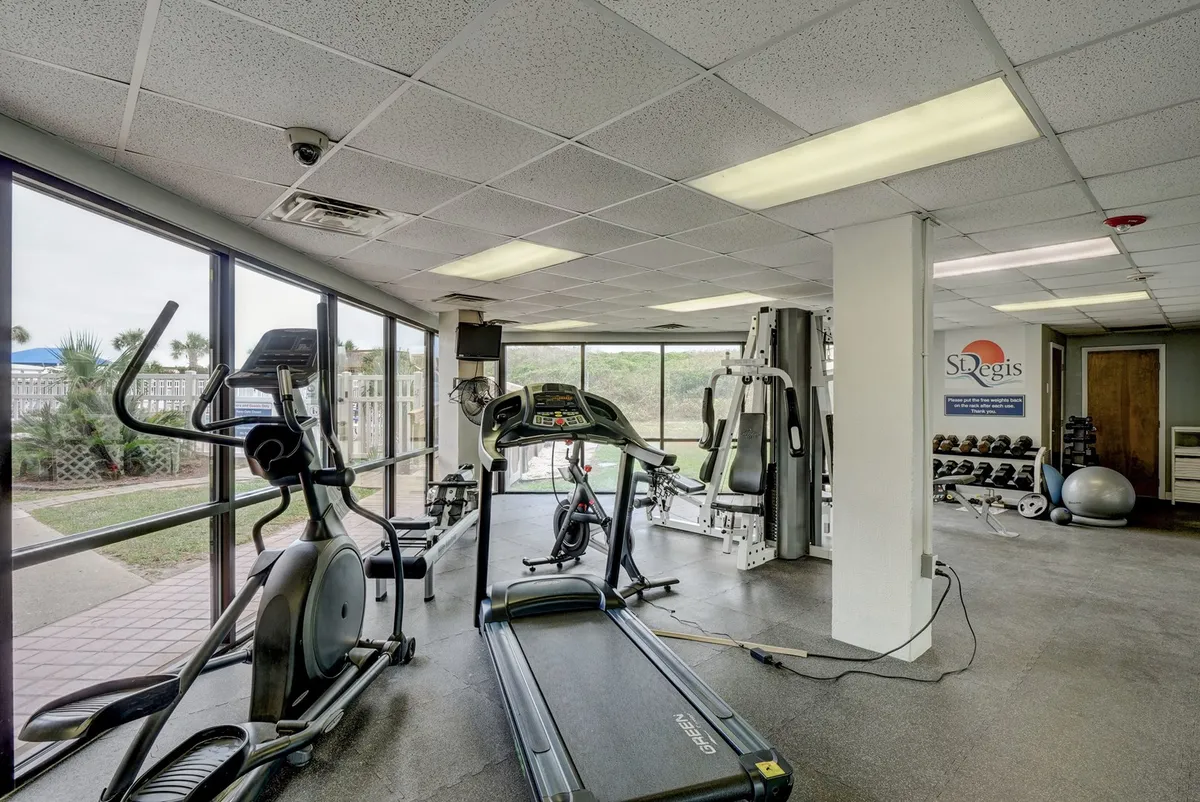 A bright fitness center filled with cardio and weight equipment, including treadmills, ellipticals, and large windows that bring in natural light. The setting is dynamic, motivating, and well-equipped for daily exercise routines.